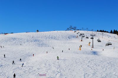 People on sand against clear blue sky
