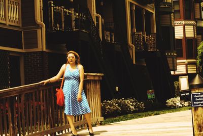 Portrait of young woman with umbrella walking in city