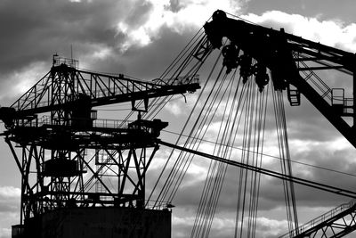 Low angle view of silhouette cranes against sky