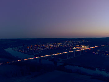 Illuminated bridge over river against sky at night