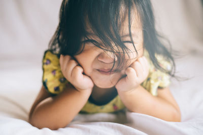 Portrait of cute girl lying on bed at home