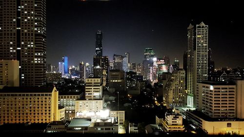 Illuminated buildings in city against sky at night