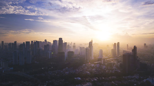 Modern buildings in city against sky during sunset