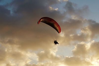 Low angle view of person paragliding against sky