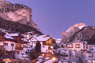 Beautiful cosy houses in selva di val gardena ski resort in italian alps at dusk during winter