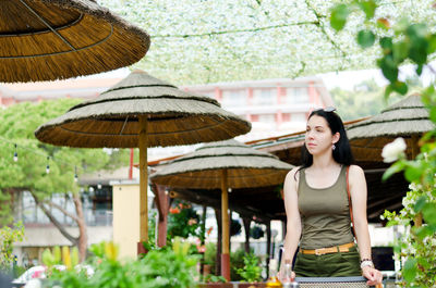 Portrait of young woman standing against palm tree