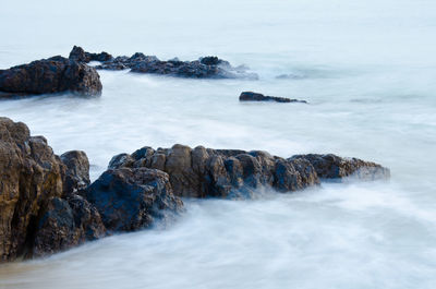 Scenic view of rocks in sea against sky