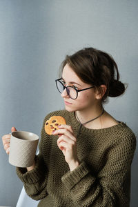 Millennial brown-haired girl in glasses drinking tea with cakes alone