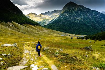 Rear view of man walking on mountain against sky