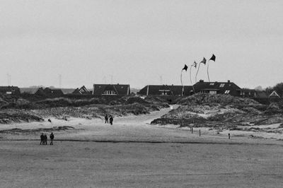 People walking on beach against clear sky