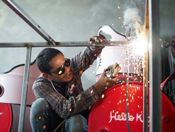 Low angle view of male welder welding metal in factory
