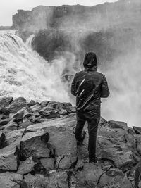 Rear view of man standing on rock against sky