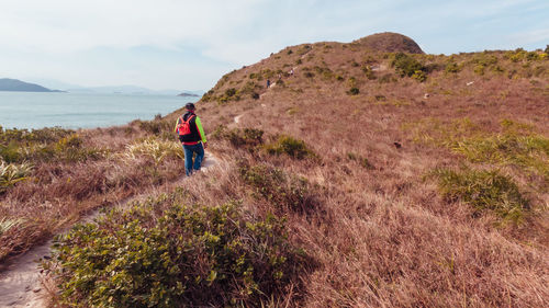 Rear view of woman standing on mountain against sky