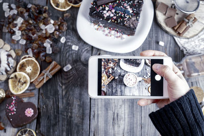 High angle view of hand photographing cake and ingredients on table