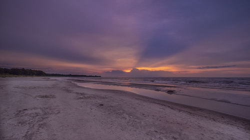 Scenic view of beach against sky at sunset
