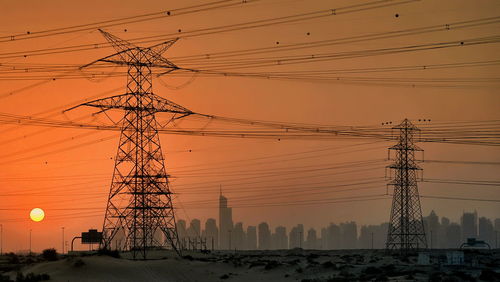Low angle view of electricity pylon against sky during sunset