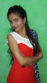 Portrait of a smiling young woman against green wall