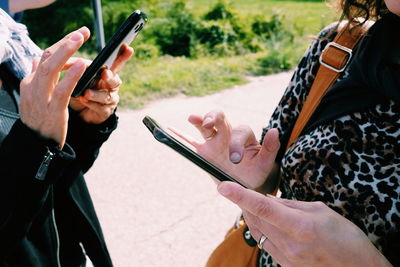 Midsection of man and woman using smart phone