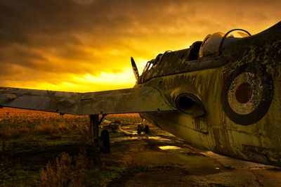 Abandoned truck on field against sky during sunset