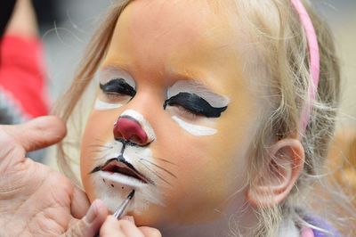 Close-up of girl having face painted like a tiger