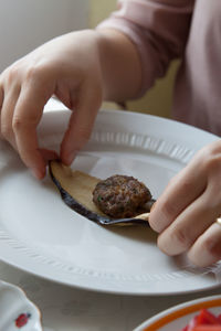 Cropped hands of woman eating food in plate at table