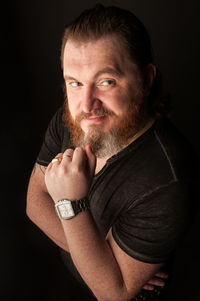 Portrait of man making face against black background