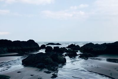 Rocks on beach against sky