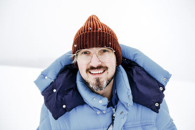 Smiling man with eyeglasses on snow during vacations