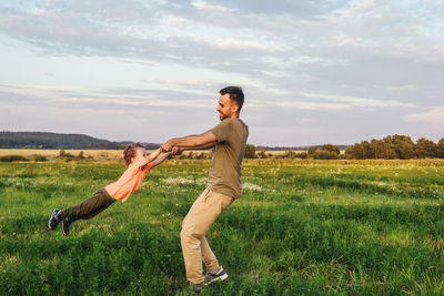 Full length of happy woman on field against sky