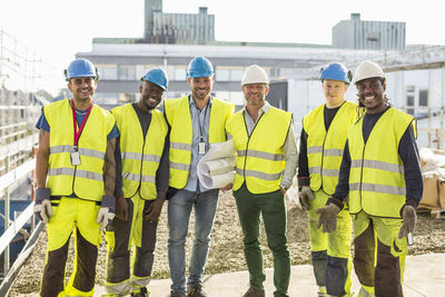 Portrait of confident construction team standing together at site