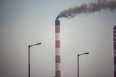 Low angle view of smoke emitting from chimney against sky