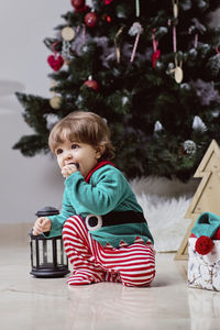 A little 12-month-old christmas elf with a christmas tree and gifts