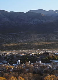 Aerial view of townscape by mountain against sky