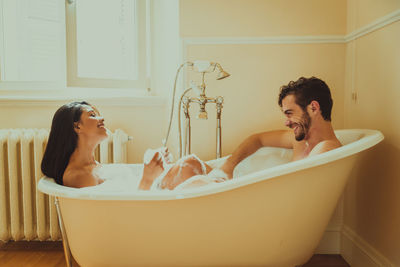 Side view of young couple sitting in bathroom