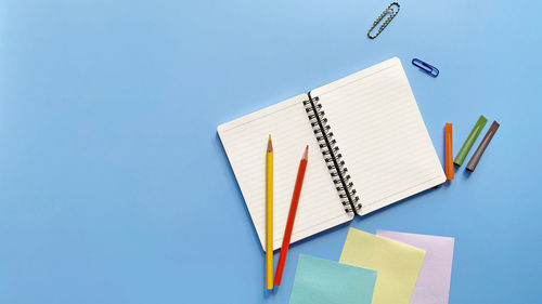 High angle view of colored pencils on table against blue background