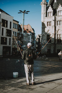 Full length of man standing on street against buildings in city