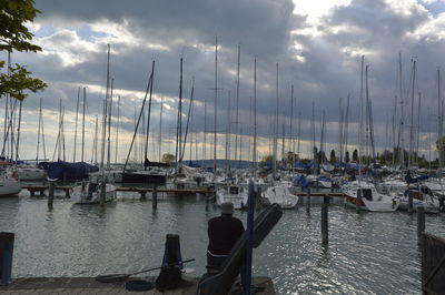 Sailboats moored at harbor against sky during sunset