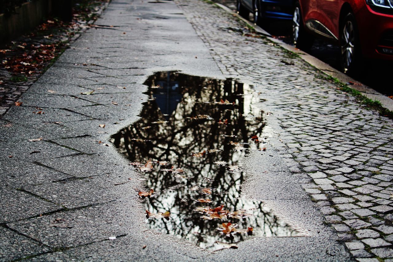 HIGH ANGLE VIEW OF WET SIDEWALK BY STREET