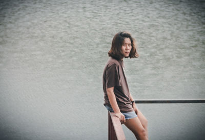 Young woman standing against water