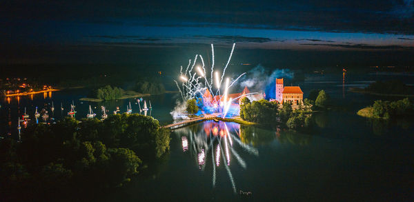 Light trails over river against sky at night