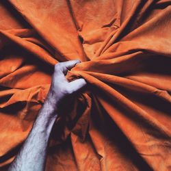 Close-up of a hand gripping bedsheet