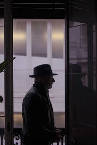 Portrait of adult man in hat and leather jacket standing on balcony. madrid, spain