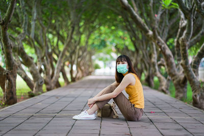 Side view of woman sitting on footpath