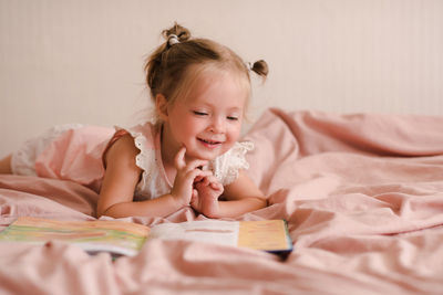 Pretty little child girl 2-3 year old reading book lying in bed closeup. good morning. childhood.