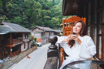 Portrait of smiling woman drinking coffee at balcony