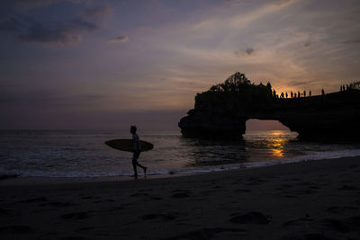 Silhouette man on beach against sky during sunset