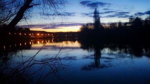 Silhouette trees by lake against sky at sunset