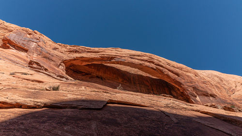 Full frame panoramic view of a natural rock arch against a clear blue sky