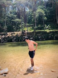 Full length of shirtless man standing in water