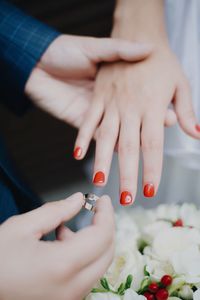 Cropped hands of bride putting ring on woman finger during wedding ceremony